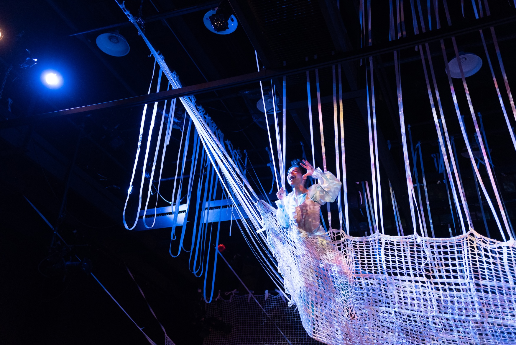 An actress suspended in webbing above stage