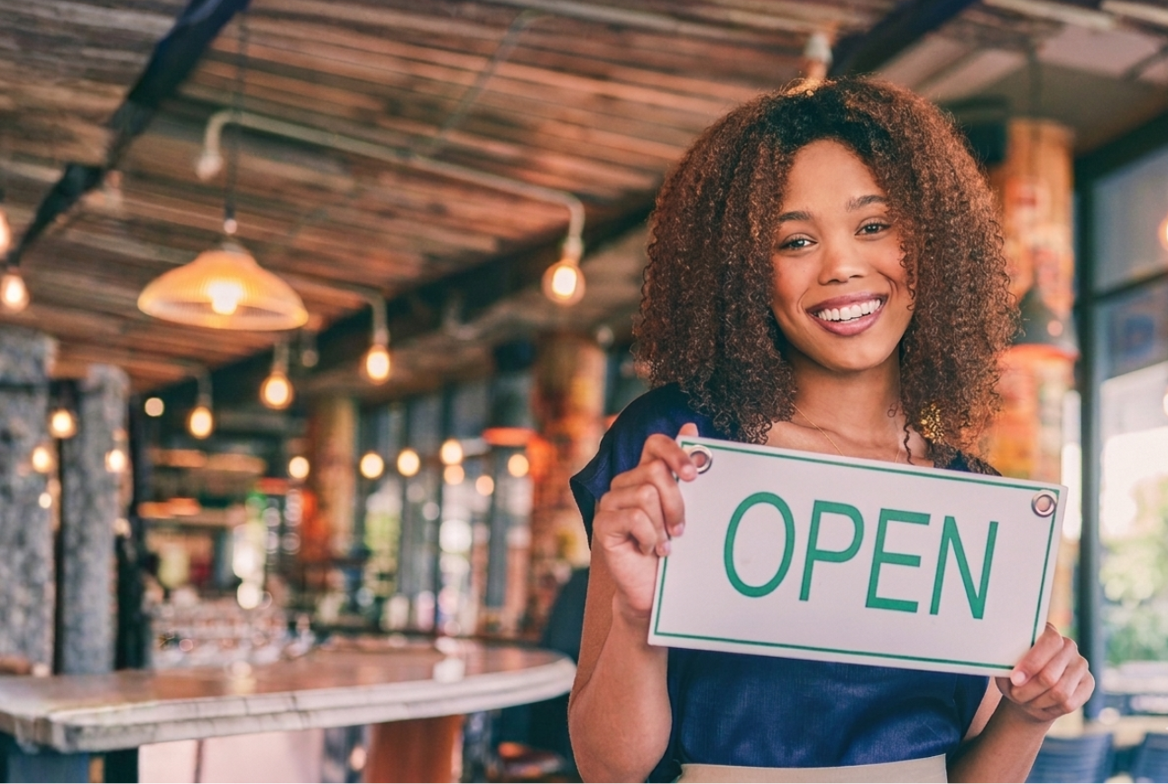 A woman holding a sign that says open