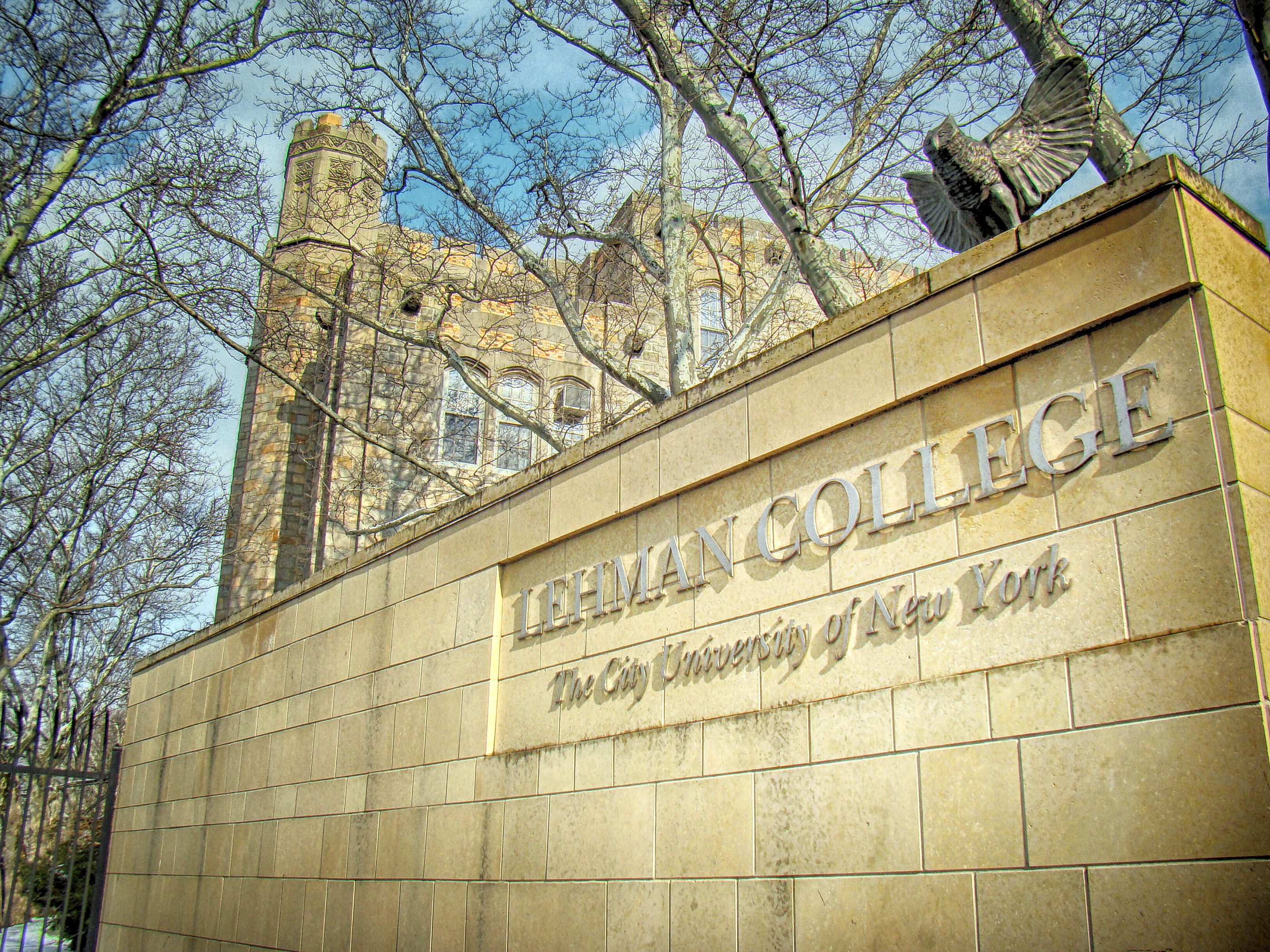 A stone wall at an entrance to the Lehman campus with a sign that reads Lehman College The City University of New York.