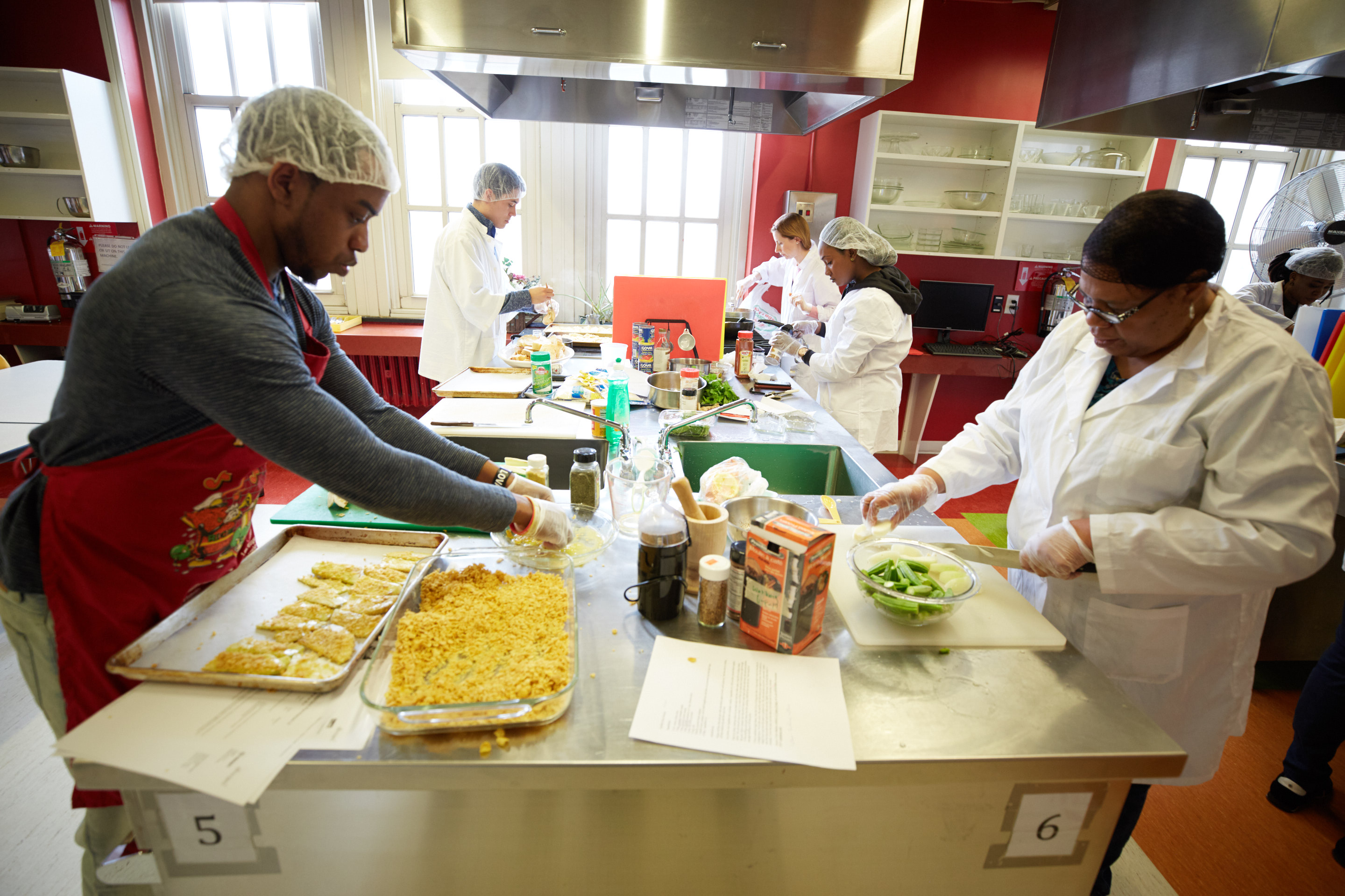 Students preparing food on a work table in a kitchen