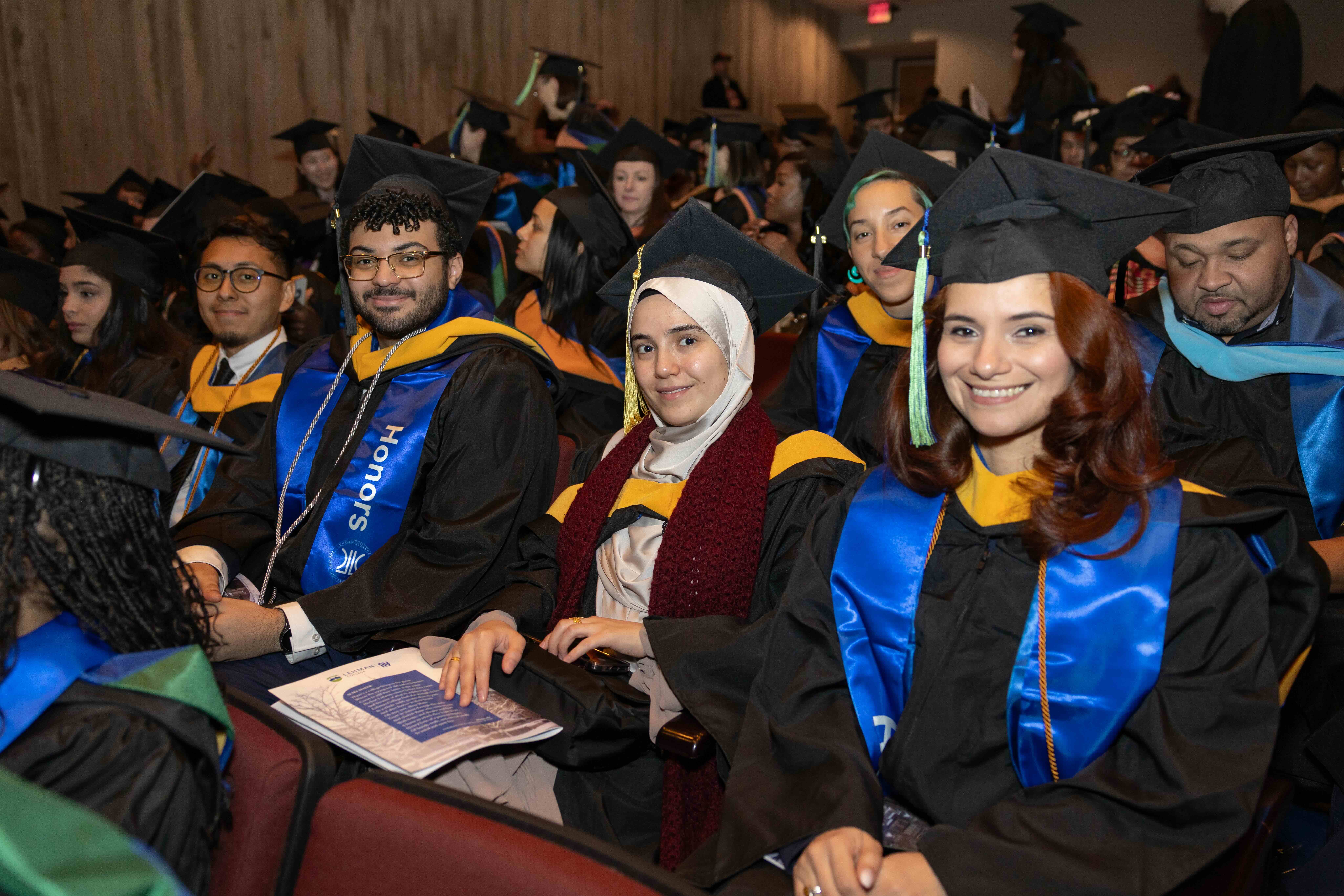 graduating students in regalia sitting down.