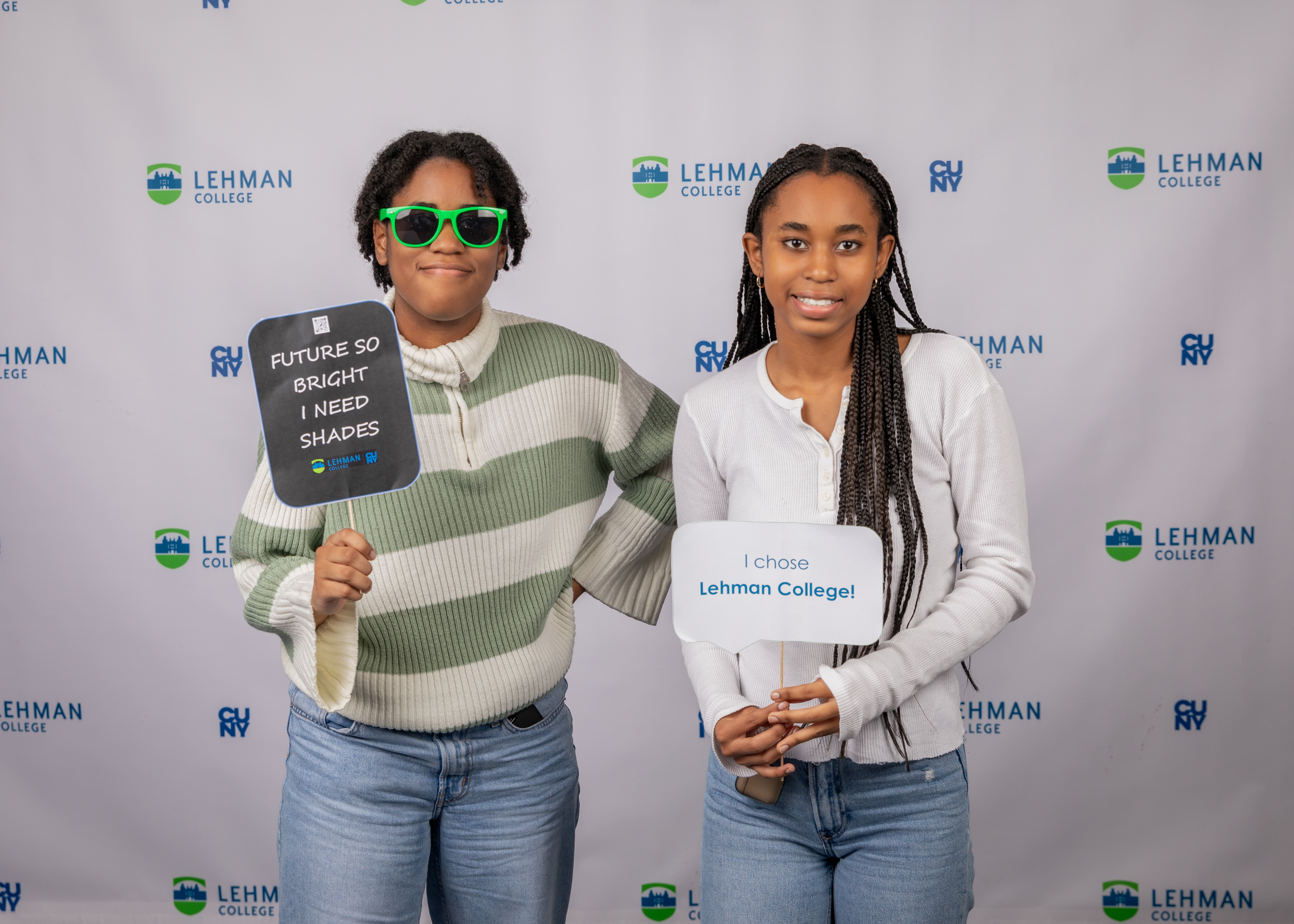 Two high school students hold signs that they chose Lehman College