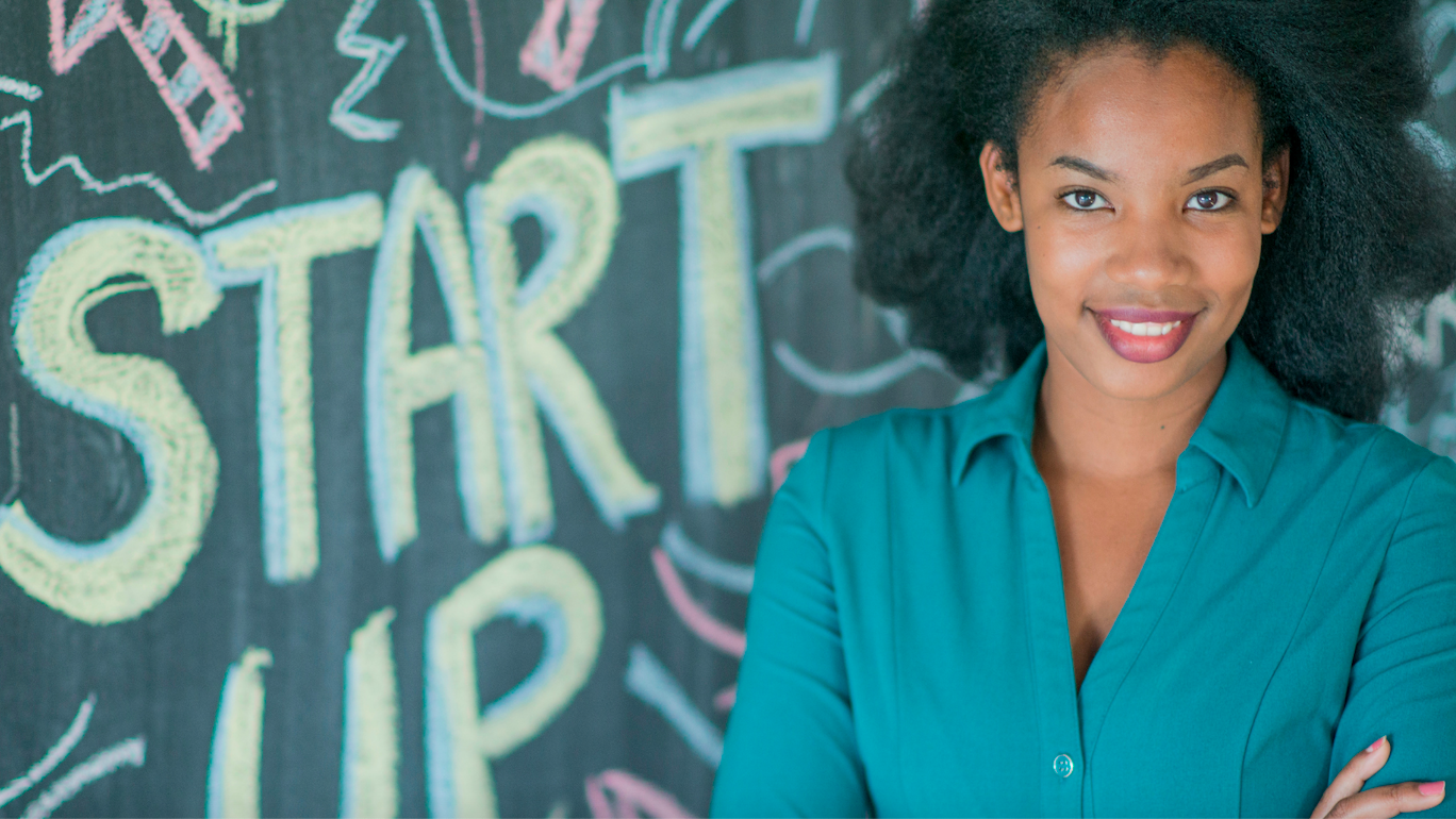 Woman posed in front of a sign that reads Start Up