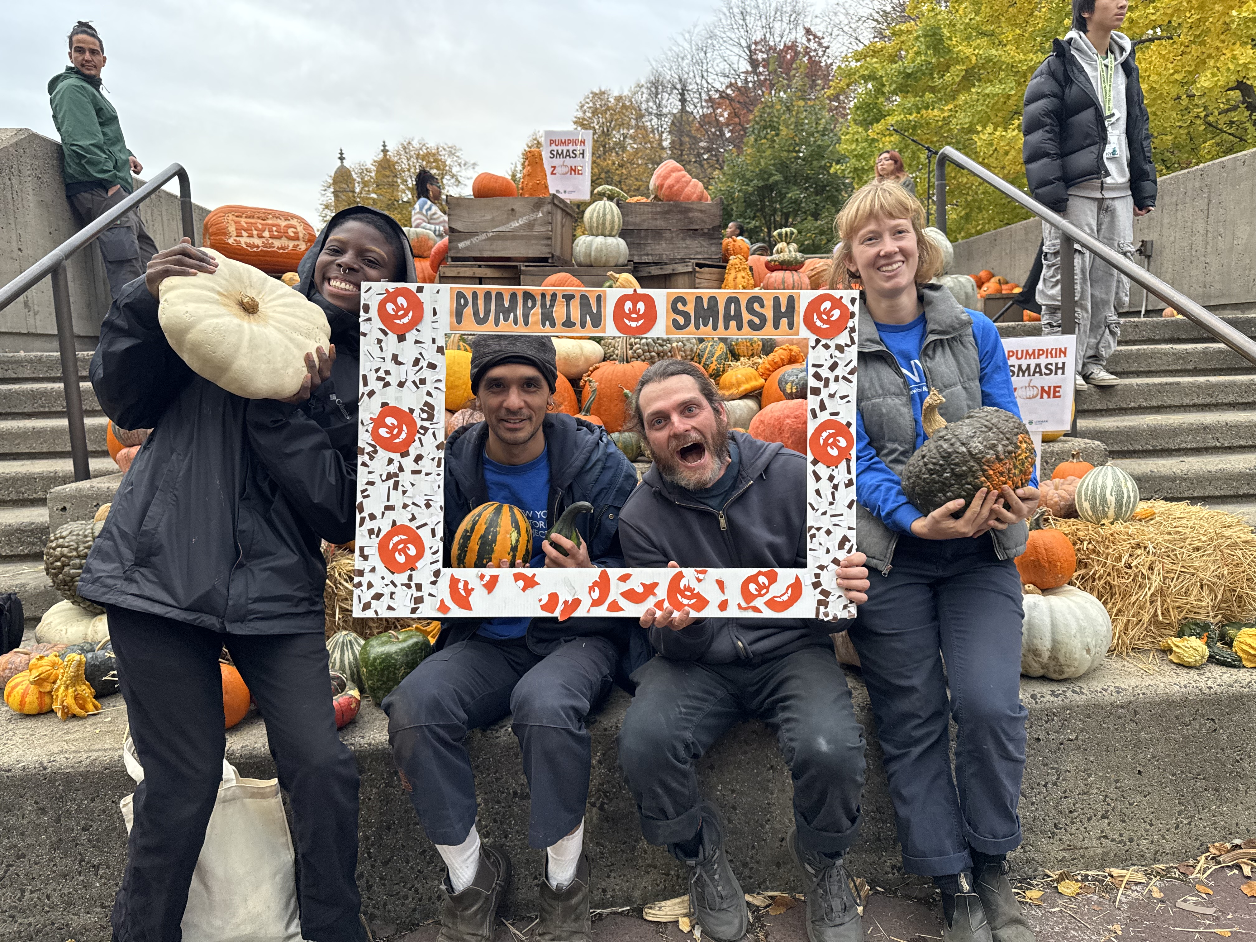 A group of adults holding a large decorative photo frame around their faces that says 