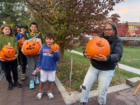 Children lined up holding jack o'lanterns