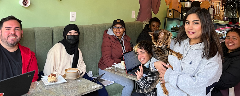 Smiling students in a cafe, one holding a cat